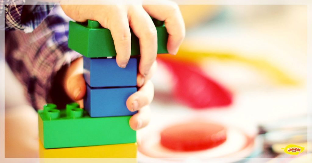 a kid's hand with a green lego-like blocks